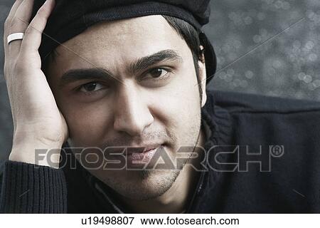 Stock Photo - Portrait of a young man with his hand on his head. Fotosearch