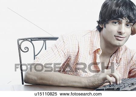 Stock Photography - Portrait of a young man working on a computer keyboard. Fotosearch