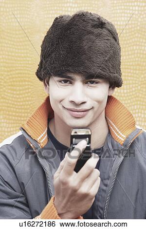 Portrait of a young man holding a mobile phone View Large Photo Image Stock Photograph - Portrait of a young man holding a mobile phone. Fotosearch
