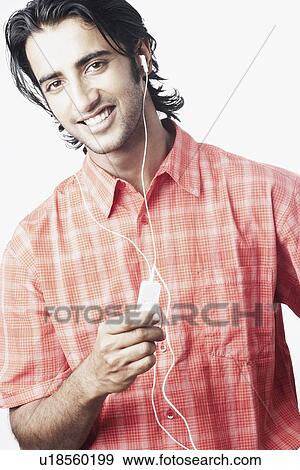 Portrait of a young man listening to an MP3 player View Large Photo Image Stock Photo - Portrait of a young man listening to an MP3 player. Fotosearch