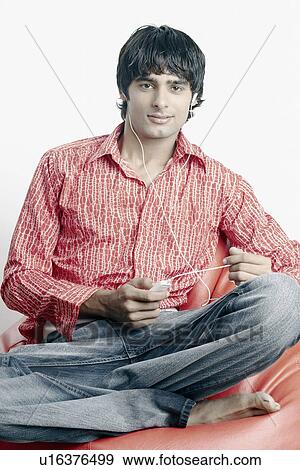 Portrait of a young man sitting on a bean bag and listening to music View Large Photo Image Stock Photo - Portrait of a young man sitting on a bean bag and listening to music. Fotosearch