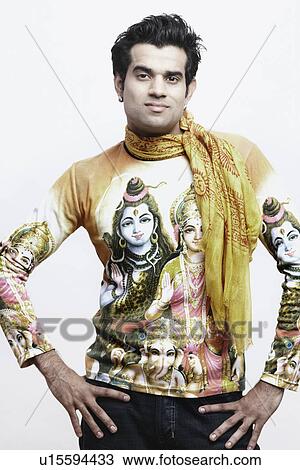 Stock Image - Portrait of a young man standing with arms akimbo. Fotosearch