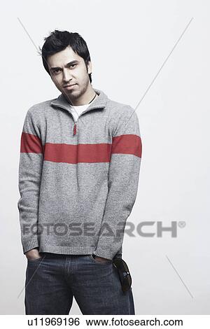 Stock Photograph - Portrait of a young man standing with his hands in his pockets. Fotosearch