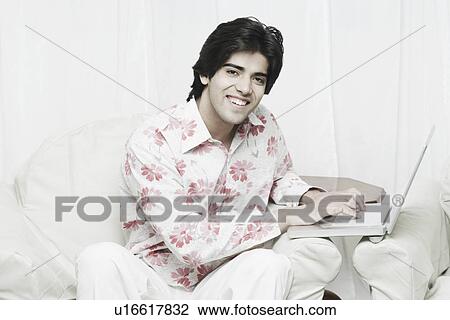 Portrait of a young man using a laptop View Large Photo Image Stock Image - Portrait of a young man using a laptop. Fotosearch