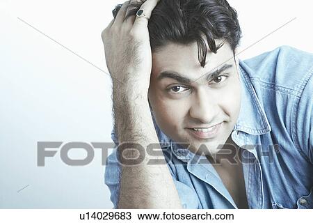 Stock Image - Portrait of a young man with his hand on his head. Fotosearch