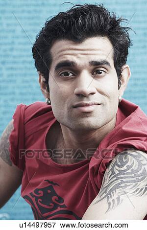 Stock Photo - Portrait of a young man with tattoos on his arm. Fotosearch