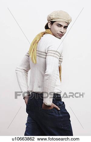 Stock Image - Rear view of a young man standing with his hands in his pockets. Fotosearch