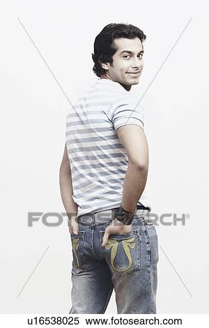 Stock Photography - Rear view of a young man standing with his hands in his pockets. Fotosearch