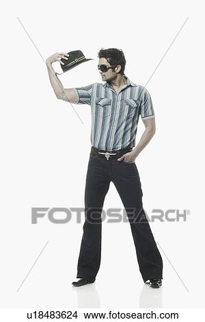 Young man holding a hat View Large Photo Image Picture - Young man holding a hat. Fotosearch