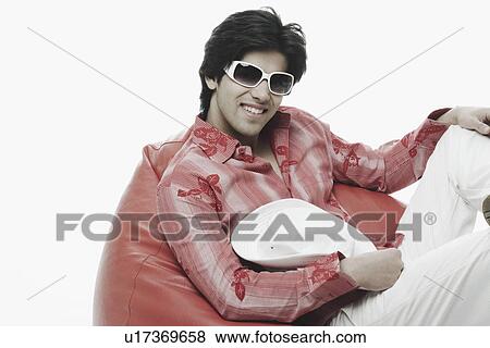 Close-up of a young man holding a hat View Large Photo Image Stock Photo - Close-up of a young man holding a hat. Fotosearch
