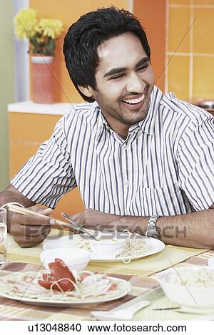 Close-up of a young man sitting at a dining table View Large Photo Image Stock Image - Close-up of a young man sitting at a dining table. Fotosearch