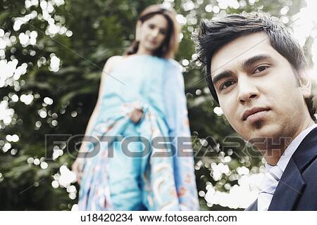 Close-up of a young man with a young woman behind him View Large Photo Image Picture - Close-up of a young man with a young woman behind him. Fotosearch