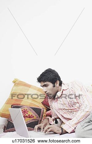 Stock Photograph - Close-up of a young man working on a laptop. Fotosearch