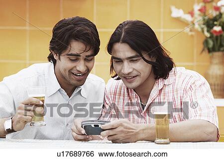 Stock Photograph - Close-up of two young men looking at a mobile phone. Fotosearch