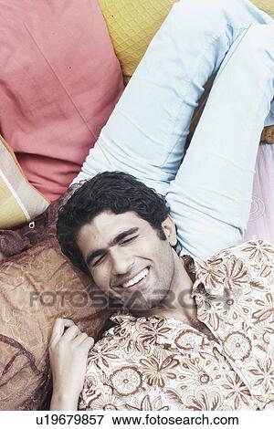 Stock Photo - High angle view of a young man with his eyes closed lying on a woman's lap. Fotosearch