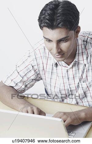 High angle view of a young man working on a laptop View Large Photo Image Stock Photograph - High angle view of a young man working on a laptop. Fotosearch