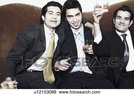 Stock Photo - Portrait of a three young men holding glasses of whiskey. Fotosearch