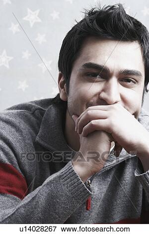 Stock Photo - Portrait of a young man covering his mouth with his hands. Fotosearch