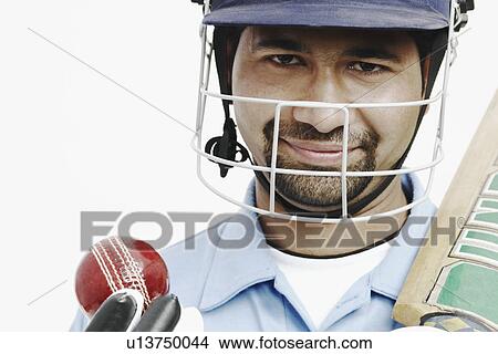 Picture - Portrait of a young man holding a cricket bat and a cricket ball. Fotosearch