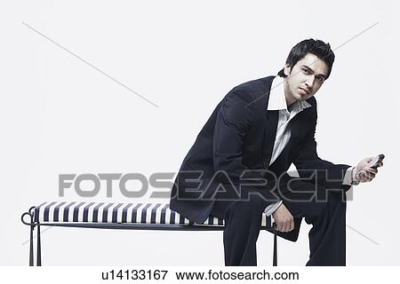 Portrait of a young man holding a mobile phone View Large Photo Image Stock Photo - Portrait of a young man holding a mobile phone. Fotosearch