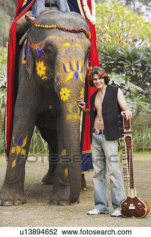 Portrait of a young man touching the trunk of an elephant View Large Photo Image Stock Image - Portrait of a young man touching the trunk of an elephant. Fotosearch