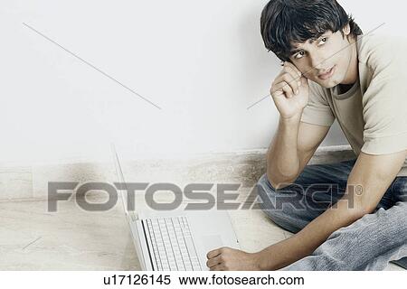 Stock Photography - Side profile of a young man sitting in front of a laptop. Fotosearch