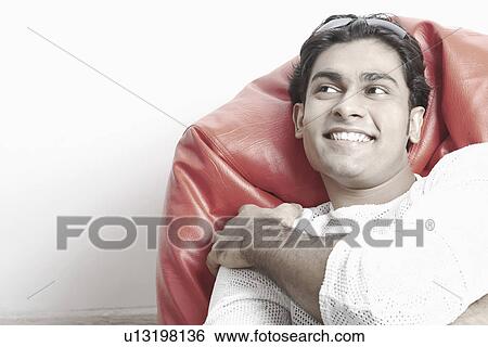 Young man sitting on a bean bag View Large Photo Image Stock Photograph - Young man sitting on a bean bag. Fotosearch