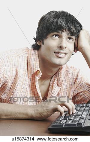 Young man working on a computer keyboard View Large Photo Image Picture - Young man working on a computer keyboard. Fotosearch