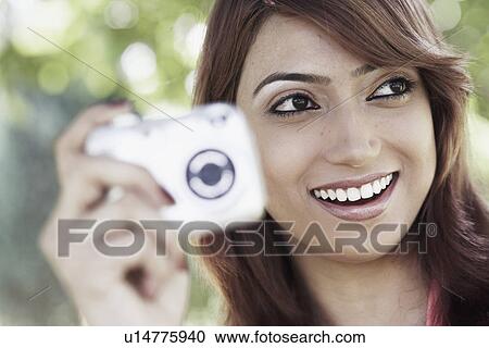Close-up of a young woman holding a digital camera View Large Photo Image Stock Image - Close-up of a young woman holding a digital camera. Fotosearch