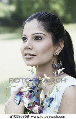 Stock Photo - Close-up of a young woman holding a bouquet of flowers. Fotosearch