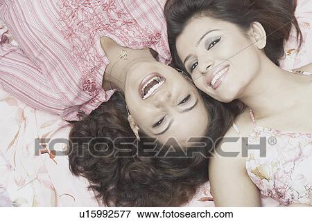 High angle view of two young women lying down and smiling View Large Photo Image Stock Photo - High angle view of two young women lying down and smiling. Fotosearch