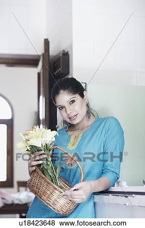 Portrait of a young woman holding a flowers in a basket View Large Photo Image Stock Photo - Portrait of a young woman holding a flowers in a basket. Fotosearch