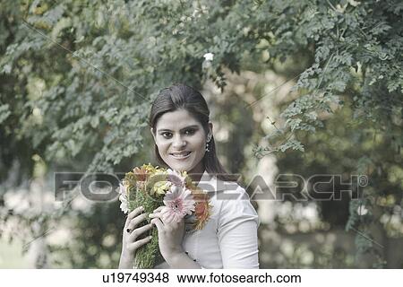 Stock Photo - Portrait of a young woman holding a bouquet of flowers. Fotosearch