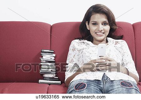 Stock Photography - Portrait of a young woman holding a mobile phone smiling. Fotosearch