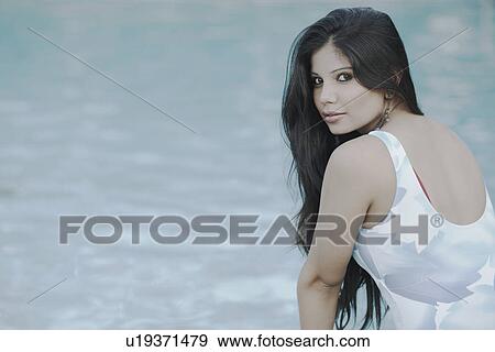 Portrait of a young woman sitting at the poolside View Large Photo Image Stock Photo - Portrait of a young woman sitting at the poolside. Fotosearch