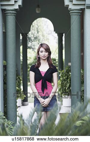 Stock Photo - Portrait of a young woman standing between two columns. Fotosearch