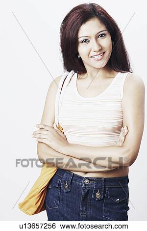 Portrait of a young woman standing with her arms crossed View Large Photo Image Stock Photograph - Portrait of a young woman standing with her arms crossed. Fotosearch