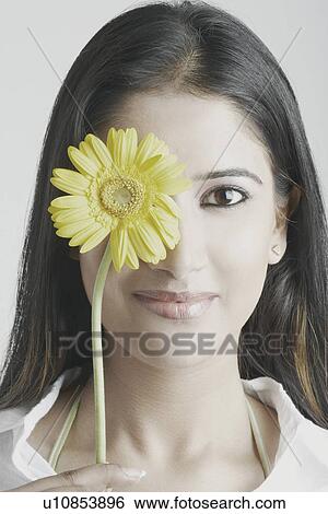 Portrait of a young woman with a flower in front of her face View Large Photo Image Stock Photograph - Portrait of a young woman with a flower in front of her face. Fotosearch
