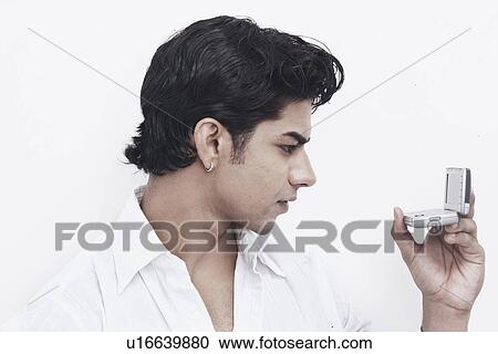 Stock Image - Close-up of a young man holding a mobile phone. Fotosearch