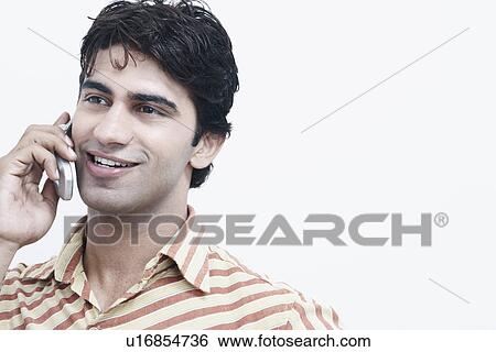 Close-up of a young man talking on a mobile phone View Large Photo Image Stock Photograph - Close-up of a young man talking on a mobile phone. Fotosearch