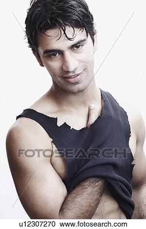 Stock Image - Close-up of a young man with his hand under his vest. Fotosearch