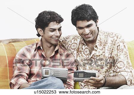 Stock Image - Close-up of two young men looking at a mobile phone. Fotosearch