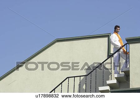 Low angle view of a young man standing on a staircases View Large Photo Image Stock Image - Low angle view of a young man standing on a staircases. Fotosearch