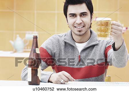 Portrait of a young man holding a beer stein View Large Photo Image Stock Image - Portrait of a young man holding a beer stein. Fotosearch