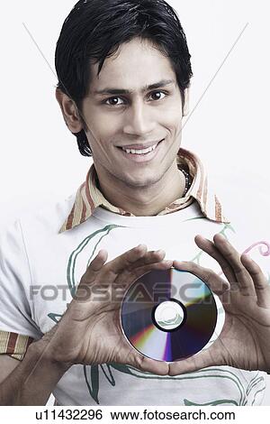 Portrait of a young man holding a CD View Large Photo Image Stock Photograph - Portrait of a young man holding a CD. Fotosearch