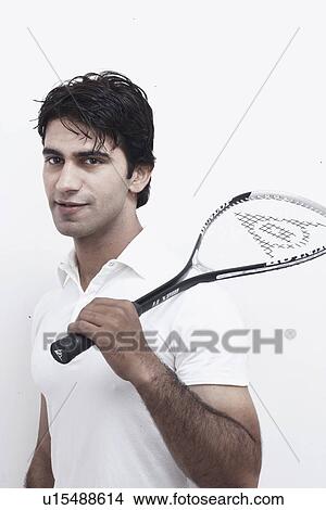 Picture - Portrait of a young man holding a squash racket. Fotosearch