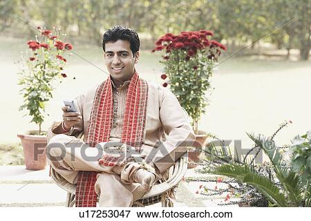 Stock Photo - Portrait of a young man operating a mobile phone. Fotosearch