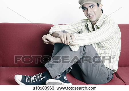 Portrait of a young man sitting on a couch View Large Photo Image Stock Image - Portrait of a young man sitting on a couch. Fotosearch
