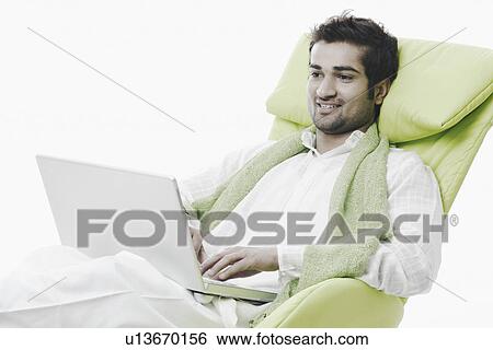 Portrait of a young man sitting with a laptop View Large Photo Image Stock Photograph - Portrait of a young man sitting with a laptop. Fotosearch