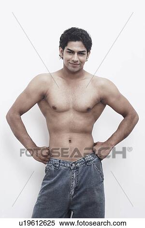 Stock Photography - Portrait of a young man with arms akimbo. Fotosearch